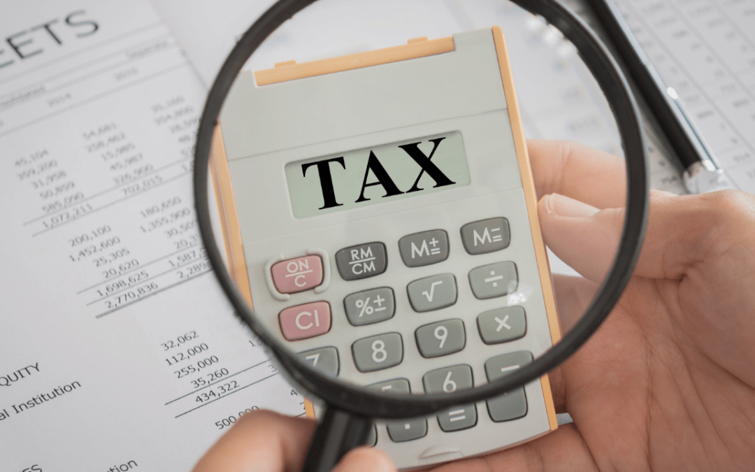 Tax adjustments: Take responsibility for your tax - image of a magnifying glass over a calculator with the word TAX on it.