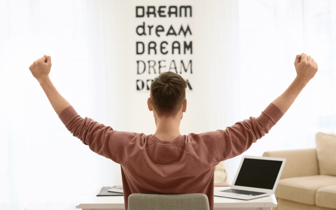 5 useful motivation tips for solopreneurs: A freelancer working in his home office with raised hands to show that he has succeeded in something.